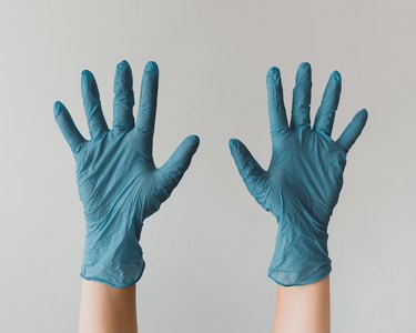 person wearing blue latex gloves and lifting their hands in the air