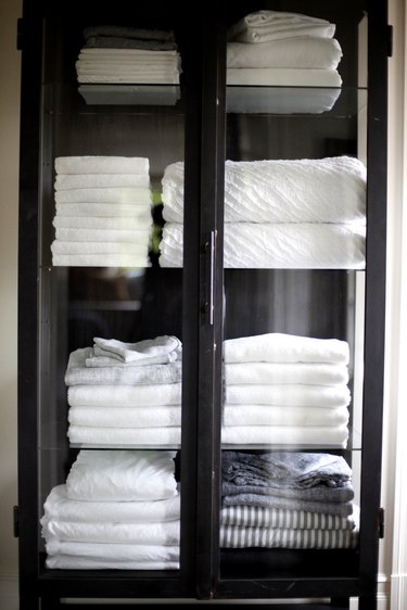wood cabinet with glass doors for bathroom towel storage idea