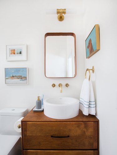 guest bathroom idea with a white bowl sink on top of a wooden vanity in a white guest bathroom