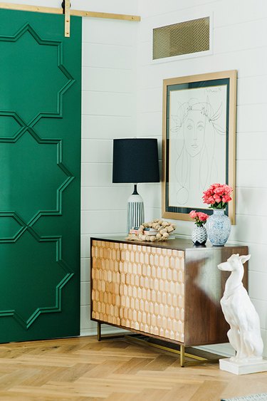 Traditional entryway table with green door and decorative accents