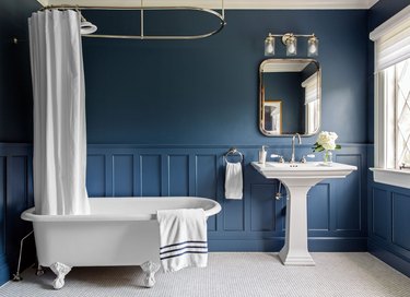 blue apartment bathroom idea with wainscoting and clawfoot tub with pedestal sink
