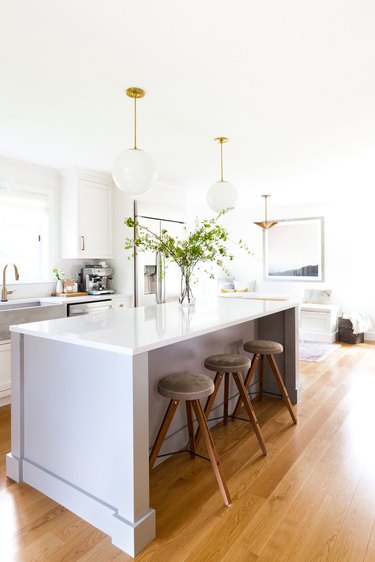 White kitchen with globe lights over the kitchen island.