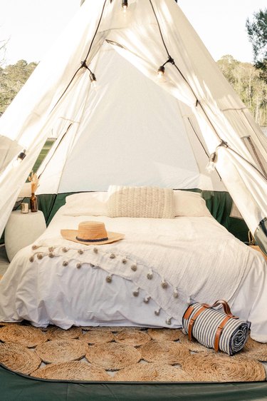 Air mattress bed inside tent with white linens and accessories