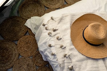 Braided jute rug, pom pom blanket and straw hat inside tent