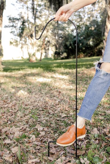 Stepping on garden stake hook to insert into ground