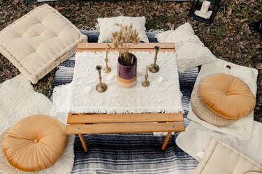 DIY boho glamping loung area with pillows, candles, flowers and poufs