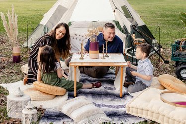 Family of four lounging around table in glamping site