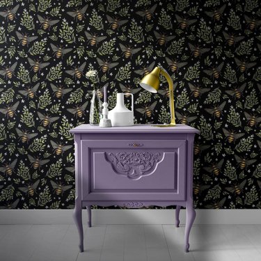 purple cabinet with bee pattern wallpaper wall behind it