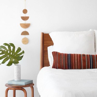 bedroom scene with striped lumbar pillow, plant, and hanging decor