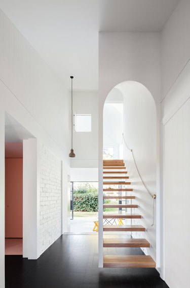 white entry with floating stairs and windows at the end of the hall