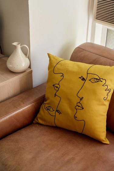 yellow pillow with face drawing on chair