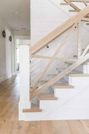 X-shaped farmhouse stair railing with cables and light wood