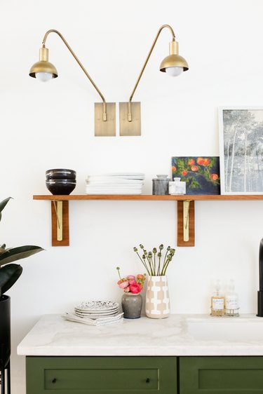 Kitchen lighting idea with brass wall sconces and green cabinets