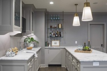 light gray basement kitchen with gold lights and glass shelves