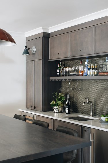 basement kitchen with gray penny tile backsplash and liquor shelf