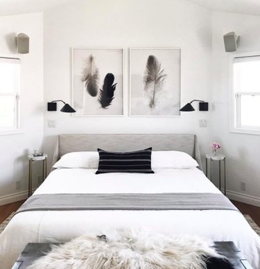 Minimal black and white symmetrical bedroom with pair of feather prints above bed