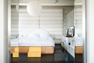 bedroom with glossy black concrete floors, large pendant light, oversized headboard