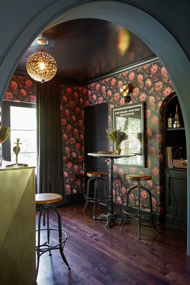 black basement bar with floral wallpaper and bistro table set