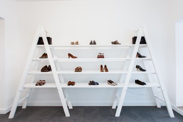 A white bookshelf against a white wall with shoes