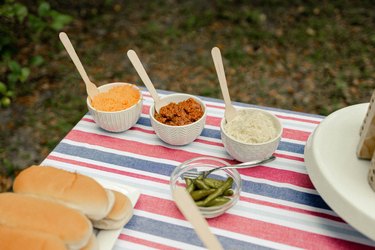 Trio of small white bowls with cheese and chili toppings for hot dogs