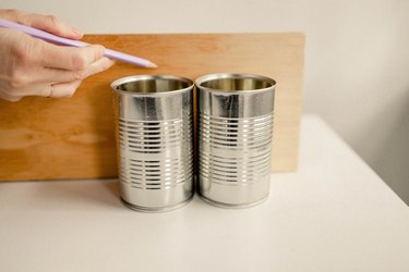 Marking height of empty soup cans on wood board