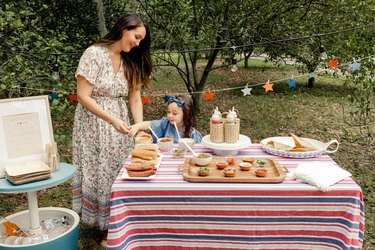 Mom and young daughter scooping toppings from the gourmet hot dog bar