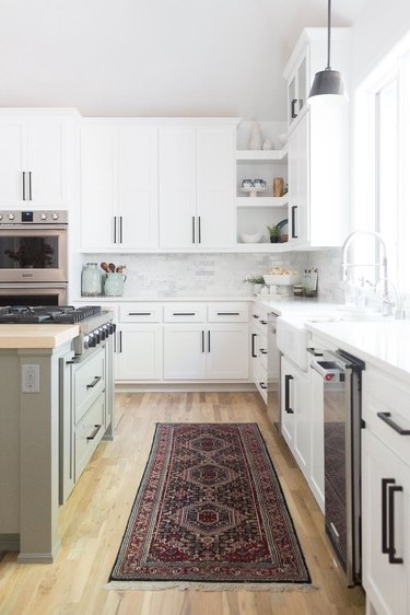 kitchen cabinet hardware idea with sage green island and wood flooring topped with area rug