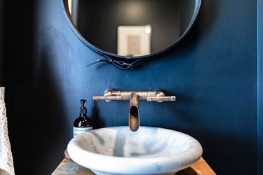A white sink basin with a contemporary faucet with a blue bathroom wall