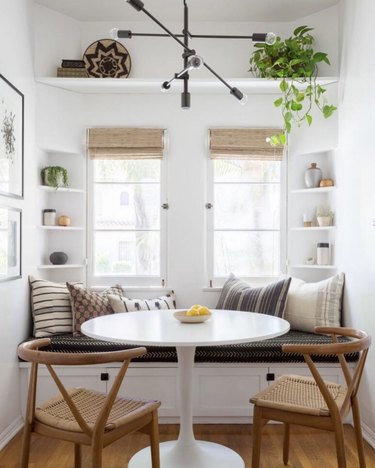 Kitchen nook idea with white tulip table and light wood wishbone chairs in a modern, bright kitchen nook