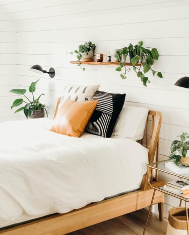 Bedroom shelving idea with houseplants and wood frame headboard