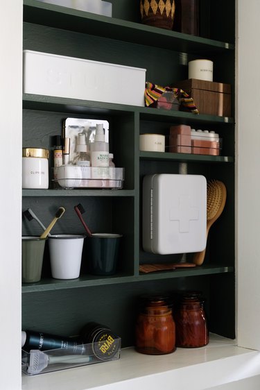 recessed medicine cabinet with green interior, beauty and medicinal products stored inside