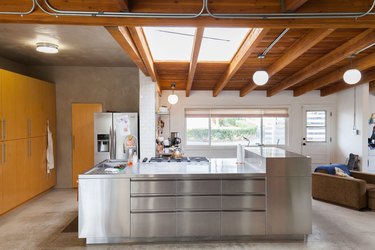 large stainless steel kitchen island in kitchen with skylights and large windows