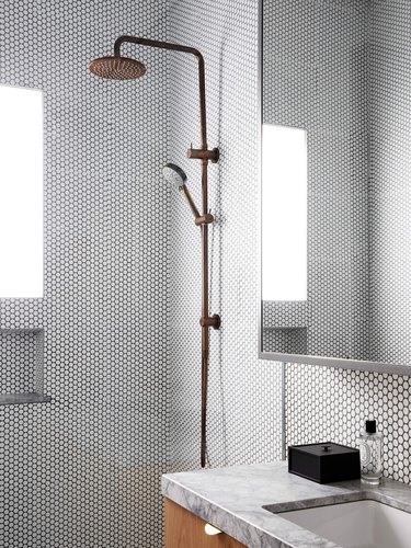 spa bathroom ideas with brass rainfall showerhead in an open shower with white penny tile