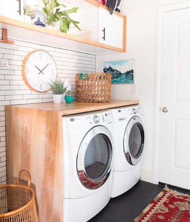 Laundry room with white subway tile, red kilim rug, and horizontal cubed wall shelf