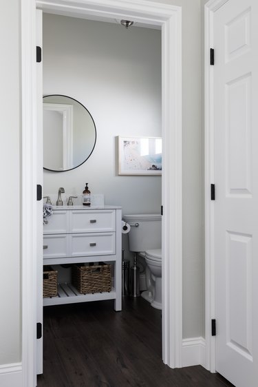 freestanding bathroom vanity and sink, toilet and circular mirror