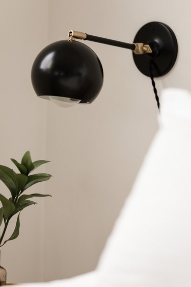 black metal bubble sconce above bedroom side table