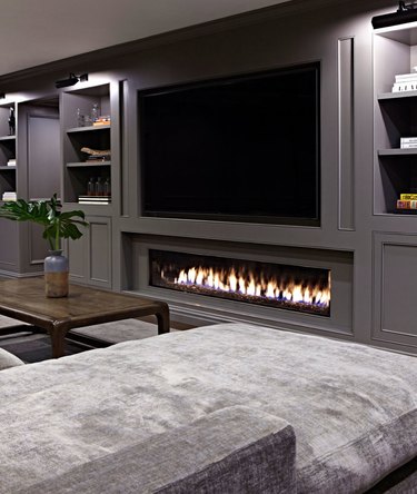basement fireplace and mounted TV with gray sectional and gray walls