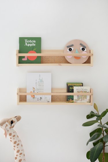 Cane shelf with childrens books and toy giraffe and plants