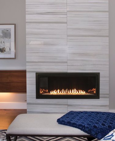 modern basement fireplace with neutral mantel and blue throw blanket