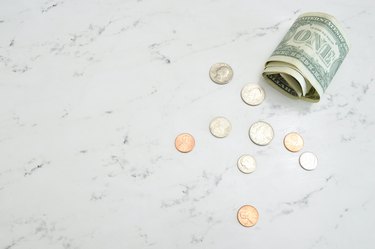 coins and dollar bills on a white marble surface