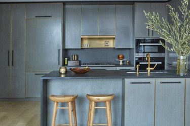 Gray quartz countertop colors, with kitchen island, wood barstools, vase with branches.