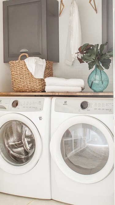 washer and dryer with basket and plant on top for basement laundry room ideas.
