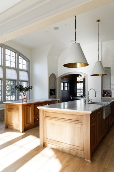 Traditional kitchen design with large white and brass pendant lights and two islands