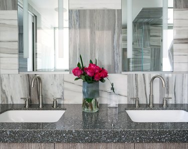 Black and white quartz countertop colors, double white sinks, marble backsplash, large mirror.