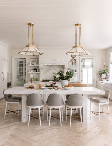 Traditional kitchen design with white and brass pendant lights and dining table