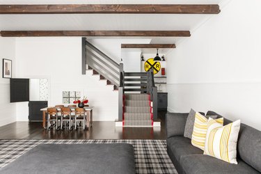 rustic basement ideas with wooden beams, white paint, and gray furniture
