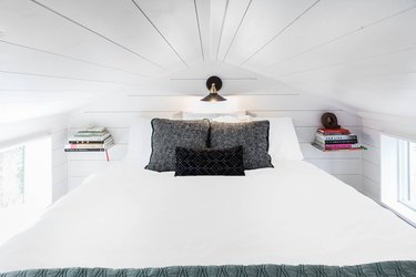 modern tiny house with white bedroom in attic like spot with two floating shelves