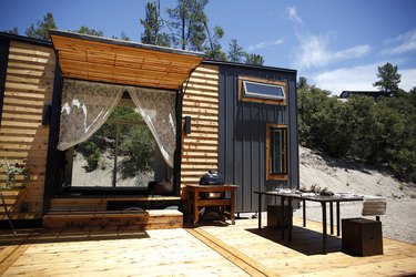 black and wooden modern tiny house with outdoor dining area