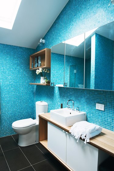modern toilet in blue tiled bathroom with skylight