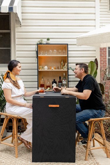 Woman and man seated at folded-down Murphy bar enjoying cocktails